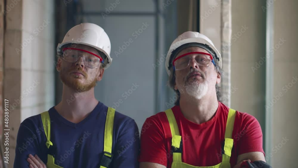 Professional confident builders with arms crossed looking at camera on construction site. Realtime Professional confident builders with arms crossed looking at camera on construction site. Realtime