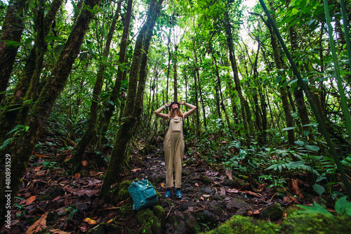 Young woman amidst trees hiking in forest at Arenal Volcano National Park, La Fortuna, Alajuela Province, Costa Rica photo
