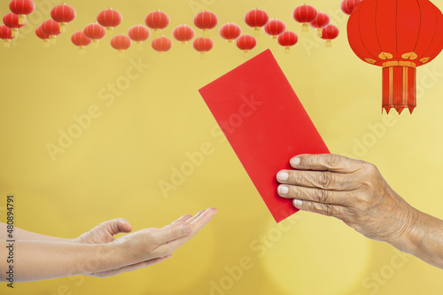 Grandmother hand giving a red envelope or hongbao to kids on chinese new year celebration. photo