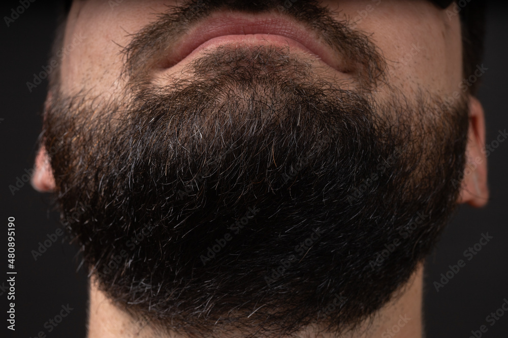 Portrait of a young bearded man face looking up, chin view from below on black isolated background Portrait of a young bearded man face looking up, chin view from below on black isolated background