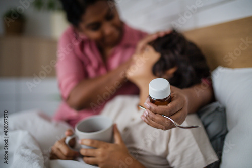 Billede på lærred Mother taking care of her sick son at home.