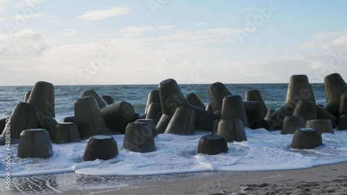 On a sunny day at the beach of Hörnum waves are hitting tetrapods in slow motion. The concrete blocks protect the coast and beach of the island Sylt from the elements of the North Sea. photo