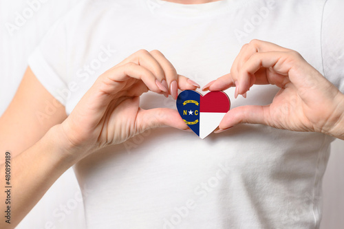 Flag of the State of North Carolina in the shape of a heart in the hands of a girl. Love North Carolina. 