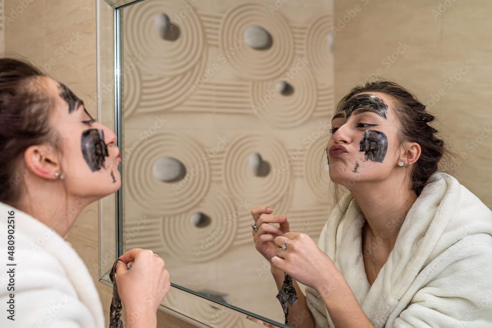 beauty near the mirror removes a black mask film from black dots in the