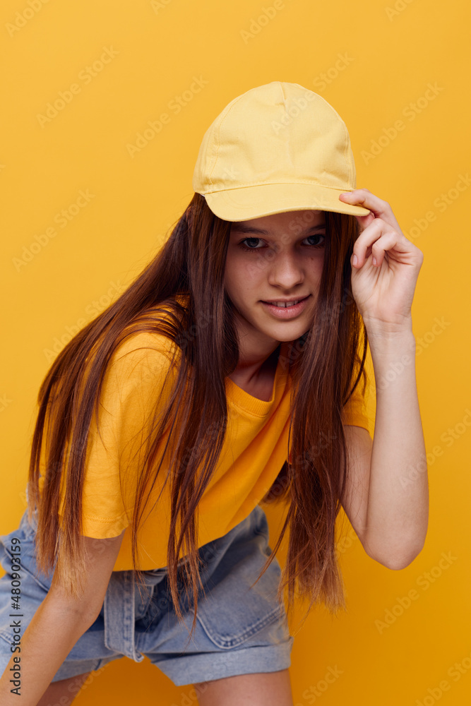 photo pretty woman posing in a yellow T-shirt and cap isolated background photo pretty woman posing in a yellow T-shirt and cap isolated background