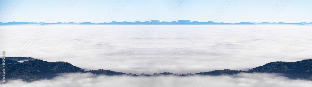 Sea of fog and snowy mountains in the background - Amazing mystical rising fog sky forest snow trees landscape in black forest ( Schwarzwald ) winter, Germany panorama - mystical snow mood..