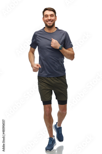 fitness, sport and healthy lifestyle concept - smiling man in sports clothes with smart watch or tracker running over white background