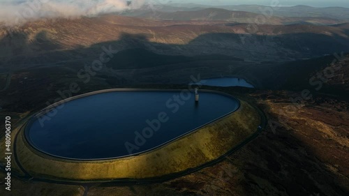 Turlough Hill, Wicklow, Ireland. January 2022 Drone gradually orbits the upper Reservoir from the west with Lough Nahanagan below and Tonelagee mountain in the background. photo