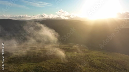 Turlough Hill, Wicklow, Ireland. January 2022 Drone gradually tracks parallel with the upper Reservoir through the mist at the summit of Tonelagee Mountain with a bright winter sky in the distance. photo