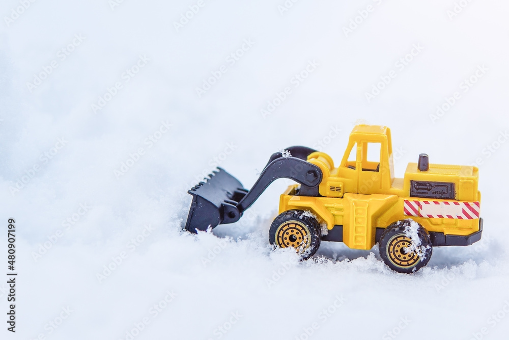 Yellow excavator removes snow on the road.