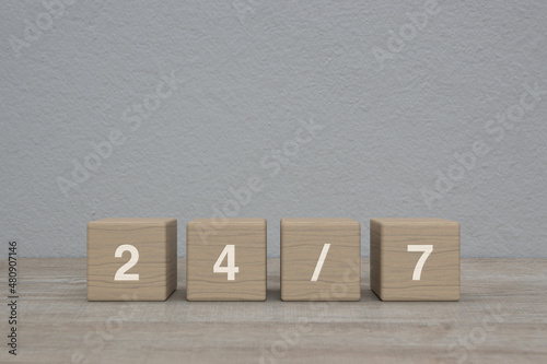 24/7 letter on wood block cubes on wooden table over white wall background, Business full time service concept