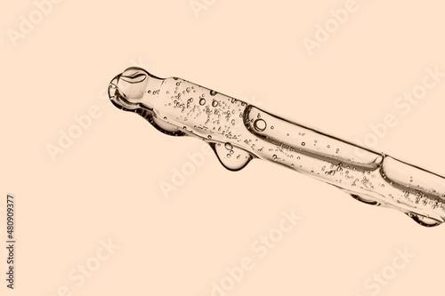 Transparent pipette with cosmetics on a beige background. photo