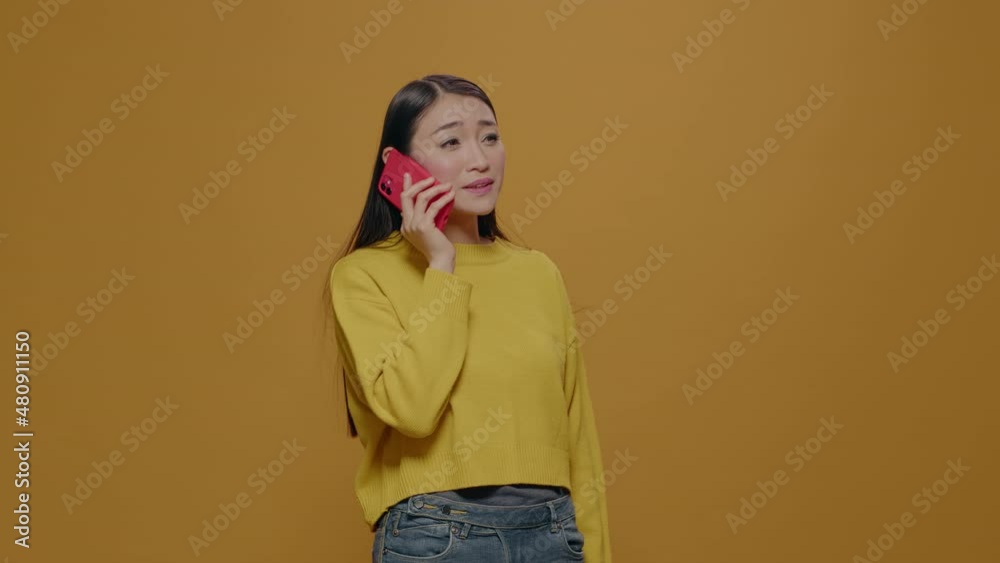 Asian woman using smartphone to have phone call conversation with friends in studio. Cheerful adult enjoying remote telecommunication on mobile phone. Modern telephone communication Asian woman using smartphone to have phone call conversation with friends in studio. Cheerful adult enjoying remote telecommunication on mobile phone. Modern telephone communication