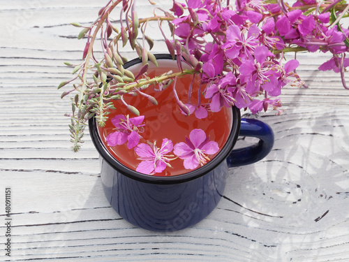 Herbal tea, chamerion angustifolium with pink flowers on a white wooden table. Useful plant epilobium parviflorum for use in herbal alternative medicine, homeopathy and cosmetology photo