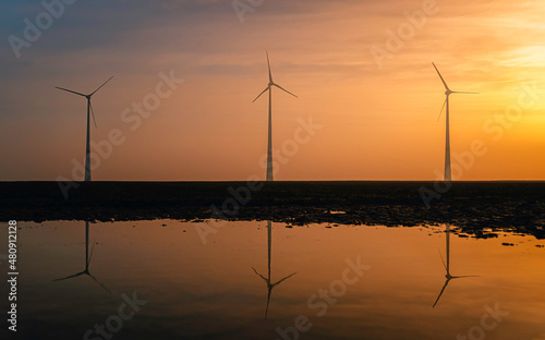 silhouette and reflections of wind turbines at sunset