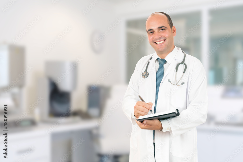 Male doctor with stethoscope holding a notebook. Smiling male doctor filling out medical form on clipboard while standing straight in hospital