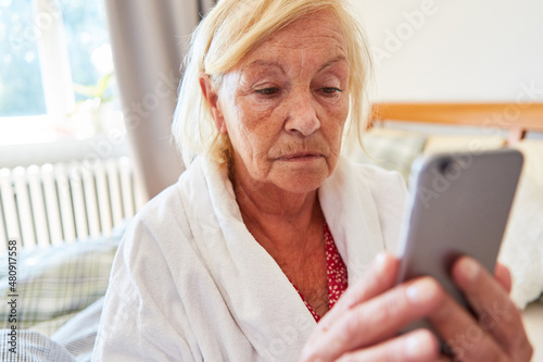 Einsame und traurige Seniorin im Pflegeheim beim Videochat photo