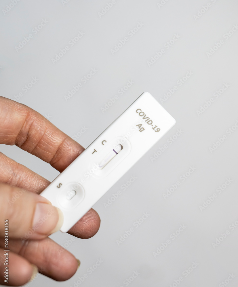 Rapid antigen test held by left hand with negative result at home in isolation regular grip