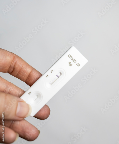 Rapid antigen test held by left hand with negative result at home in isolation regular grip