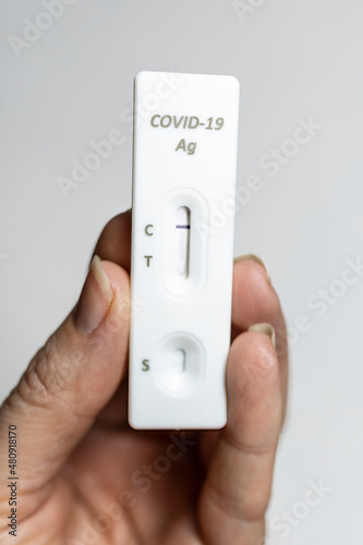 Rapid antigen test held by left hand with negative result at home in isolation bunch grip