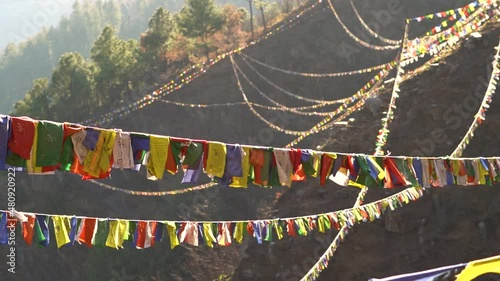 Slow motion shot of colorful Buddhist Tibetan prayer flag in front of mountains at Pangan Nyingmapa Monastery in Patlikuhal village near Manali, Himachal Pradesh, India
