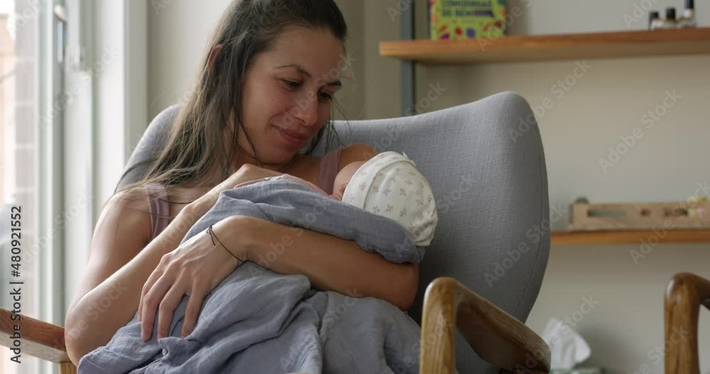 New mother smiles as she holds and stares at her new born baby girl New mother smiles as she holds and stares at her new born baby girl