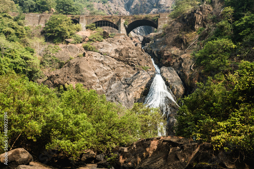Dudhsagar waterfall and old bridge in Indian state of Goa on a sunny day. photo