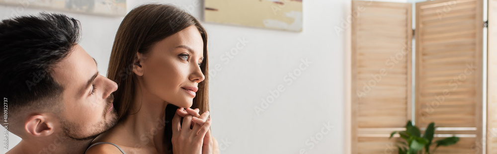 young man near sensual dreamy woman looking away in bedroom, banner. young man near sensual dreamy woman looking away in bedroom, banner.