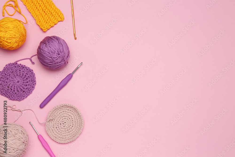 Flat lay composition with knitting threads and crochet hooks on pink background, space for text - obrazy, fototapety, plakaty 