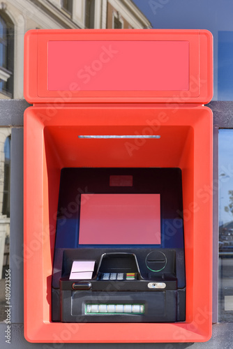 ATM machine or cashpoint for financial transactions, deposits and funds transfers with blank red screen and space for text photo