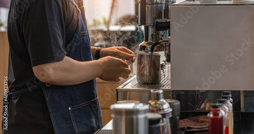 Barista is making a hot fresh coffee with machine for customer.