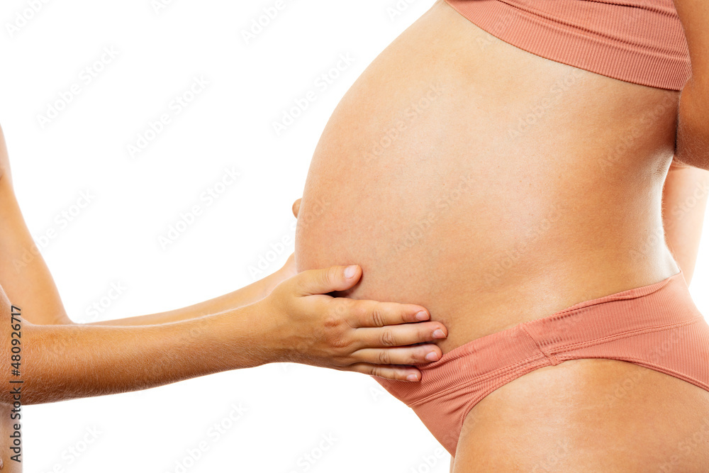 Child hands touch pregnant belly: expect a brother