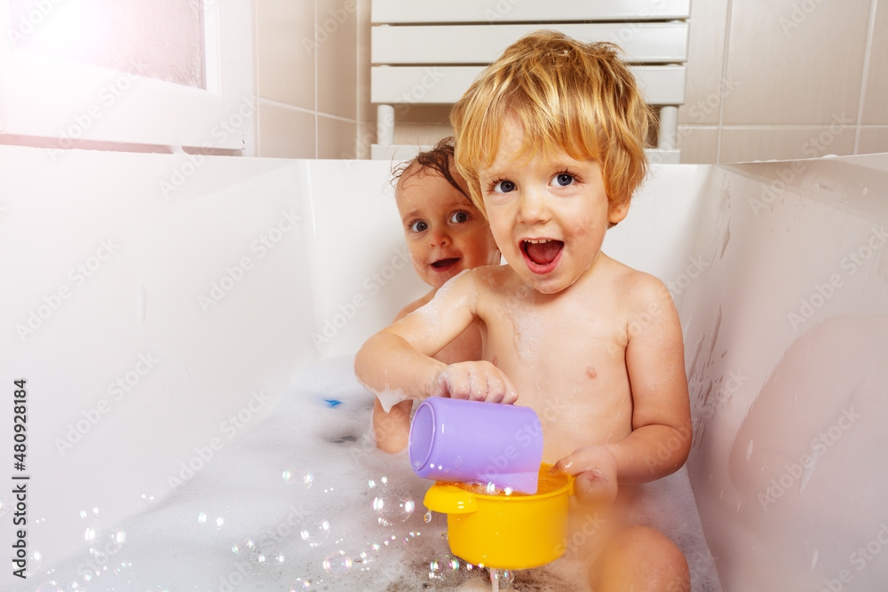 Two little babies play with soap bubbles smiling