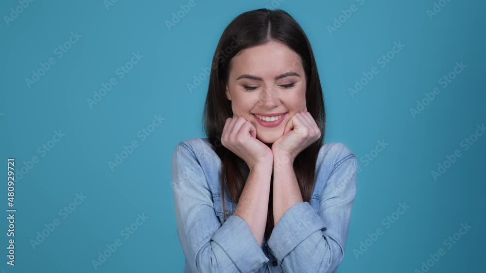 Gentle lady touch fists tender cheeks isolated blue color background Gentle lady touch fists tender cheeks isolated blue color background
