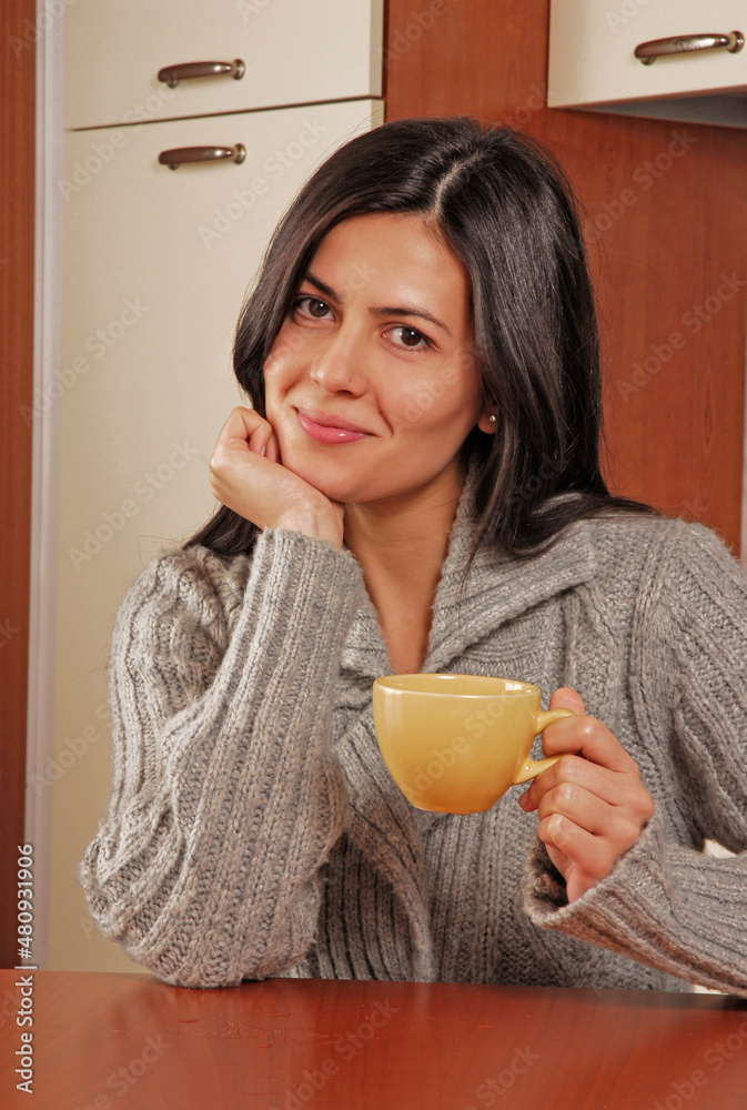 Young latin woman holding a hot drink cup in the kitchen Young latin woman holding a hot drink cup in the kitchen