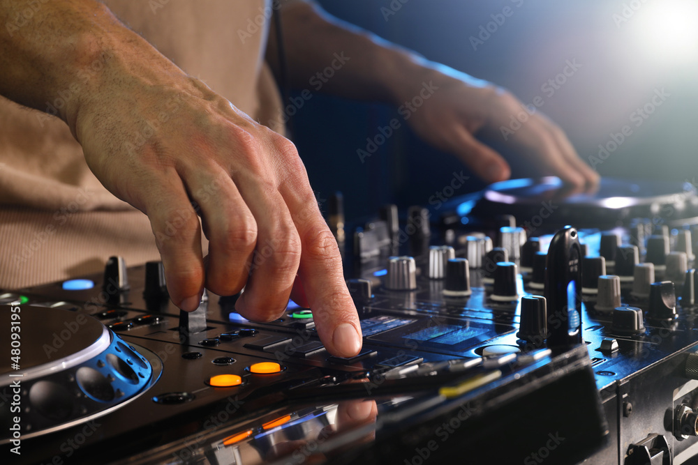 DJ creating music on modern console mixer in night club, closeup DJ creating music on modern console mixer in night club, closeup