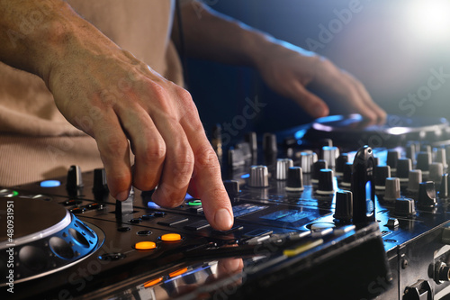 DJ creating music on modern console mixer in night club, closeup