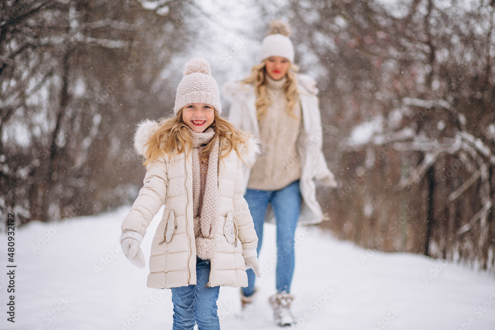 Mother with daughter walking together in a winter park