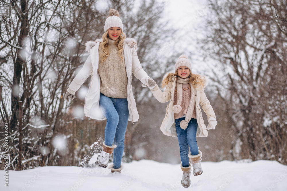 Mother with daughter walking together in a winter park