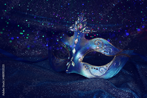 Photo of elegant and delicate Venetian mask over blue dark silk background