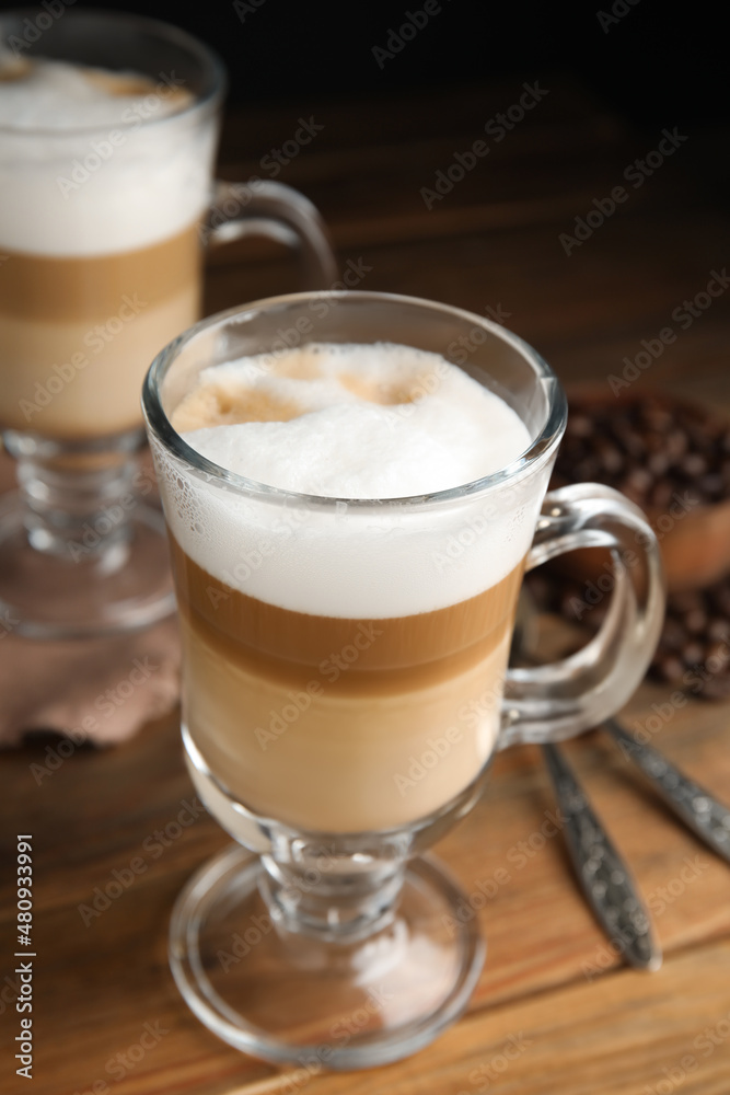 Delicious latte macchiato and coffee beans on wooden table Delicious latte macchiato and coffee beans on wooden table