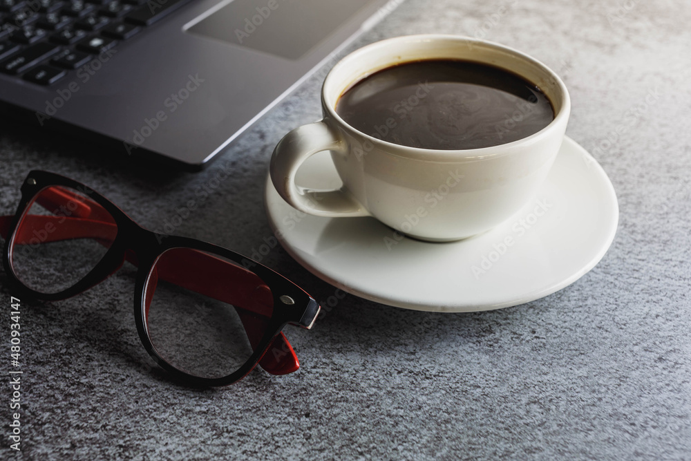 Coffee cup on desk with laptop and glasses Coffee cup on desk with laptop and glasses