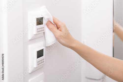 Cleaning switches and sockets with a microfiber cloth. Woman hand using wet wipe for cleaning home room door link. Sanitize surfaces prevention in hospital and public spaces against corona virus