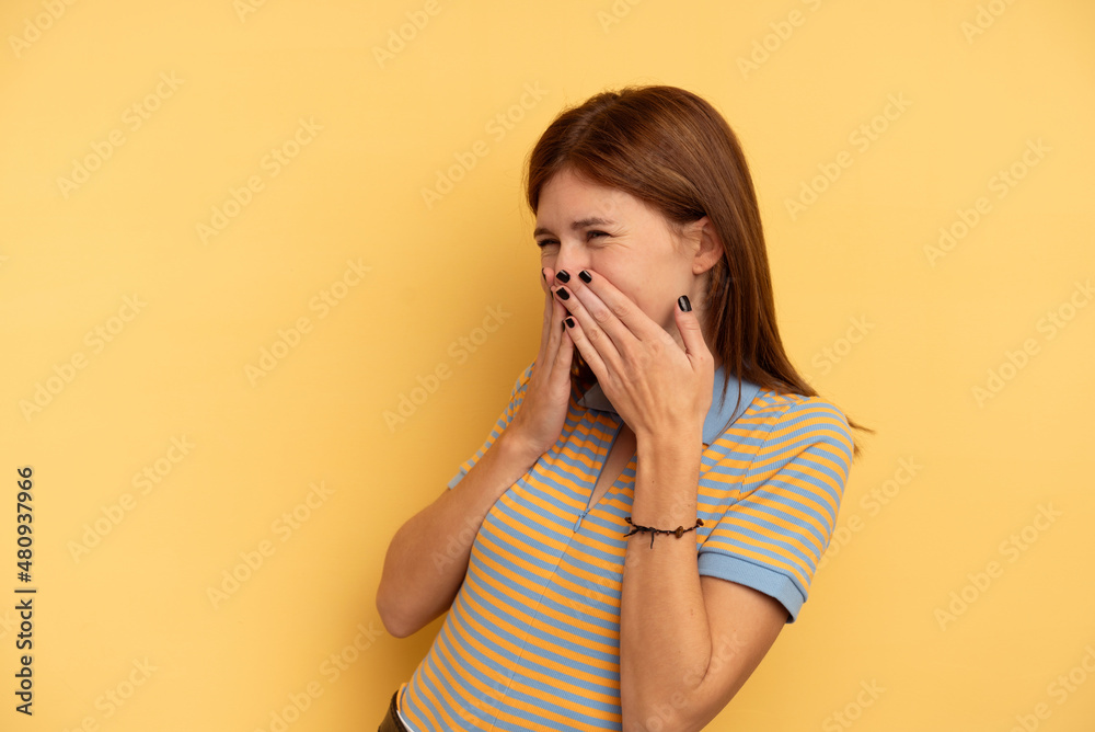 Young English woman isolated on yellow background laughing about something, covering mouth with hands. Young English woman isolated on yellow background laughing about something, covering mouth with hands.