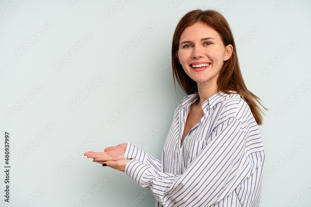 Young English woman isolated on blue background holding a copy space on a palm. Young English woman isolated on blue background holding a copy space on a palm.