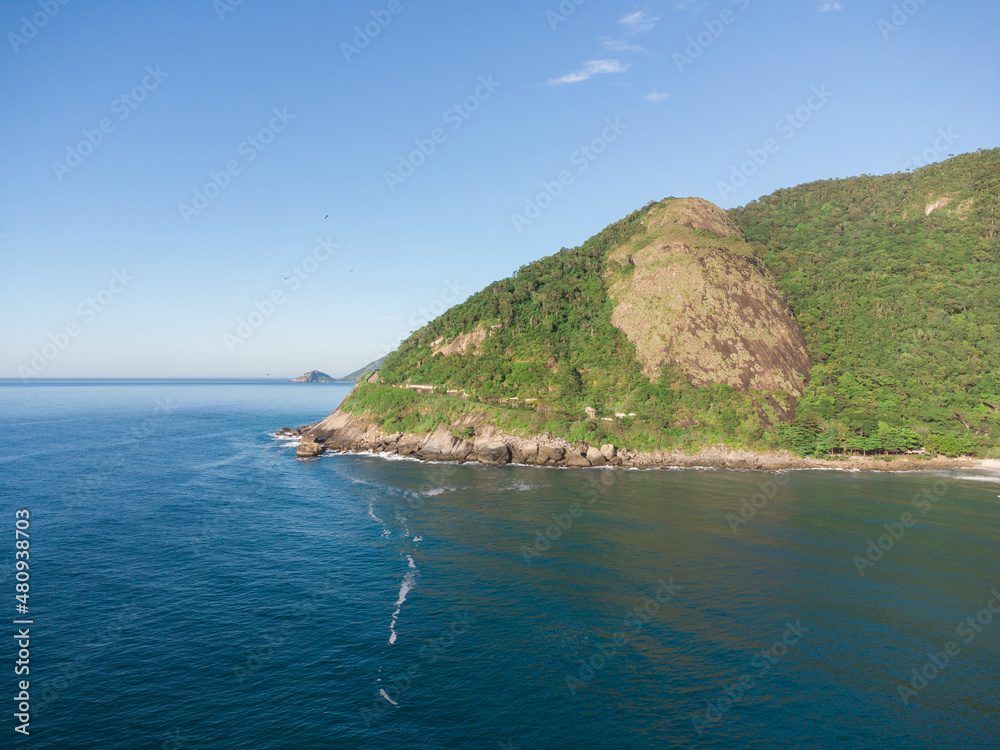 Fototapeta premium Aerial view of Prainha Beach, a paradise in the west side of Rio de Janeiro, Brazil. Big hills around. Sunny day at dawn. Greenish sea. Drone Photo