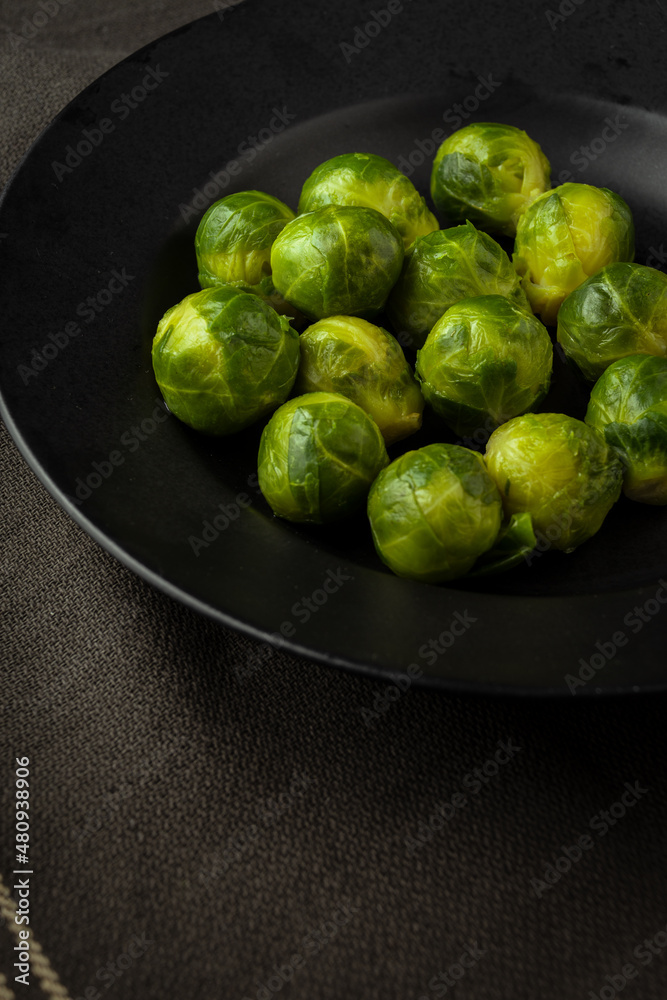 Overhead view of frozen brussels sprouts on black plate and dark cloth, selective focus, vertical, with copy space Overhead view of frozen brussels sprouts on black plate and dark cloth, selective focus, vertical, with copy space