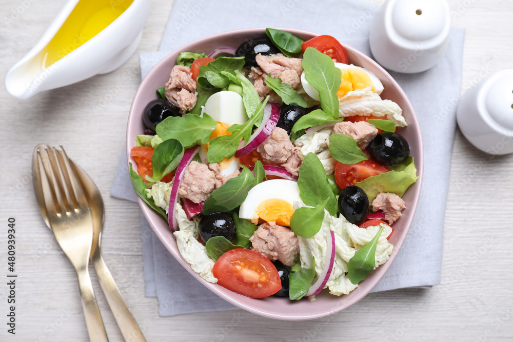 Bowl of delicious salad with canned tuna and vegetables served on white wooden table, flat lay