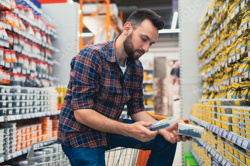 a buyer in a hardware store chooses screws and self-tapping screws for building a house.