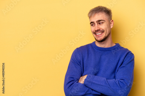 Young caucasian man isolated on yellow background smiling confident with crossed arms.